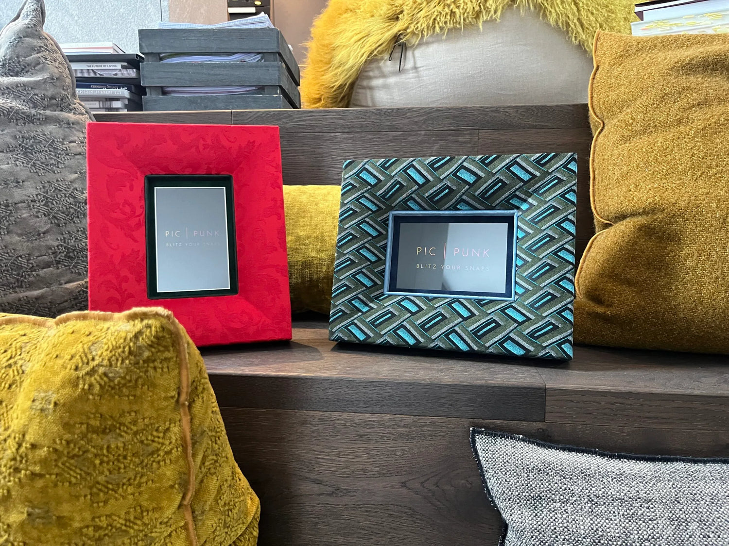 Zwei stoffbezogene Bilderrahmen von PIC | PUNK im Hoch- und Querformat, arrangiert in einem wohnlichen Ambiente mit dekorativen Kissen. Die Szene zeigt die vielseitige Einsetzbarkeit der Rahmen im Interior Design.