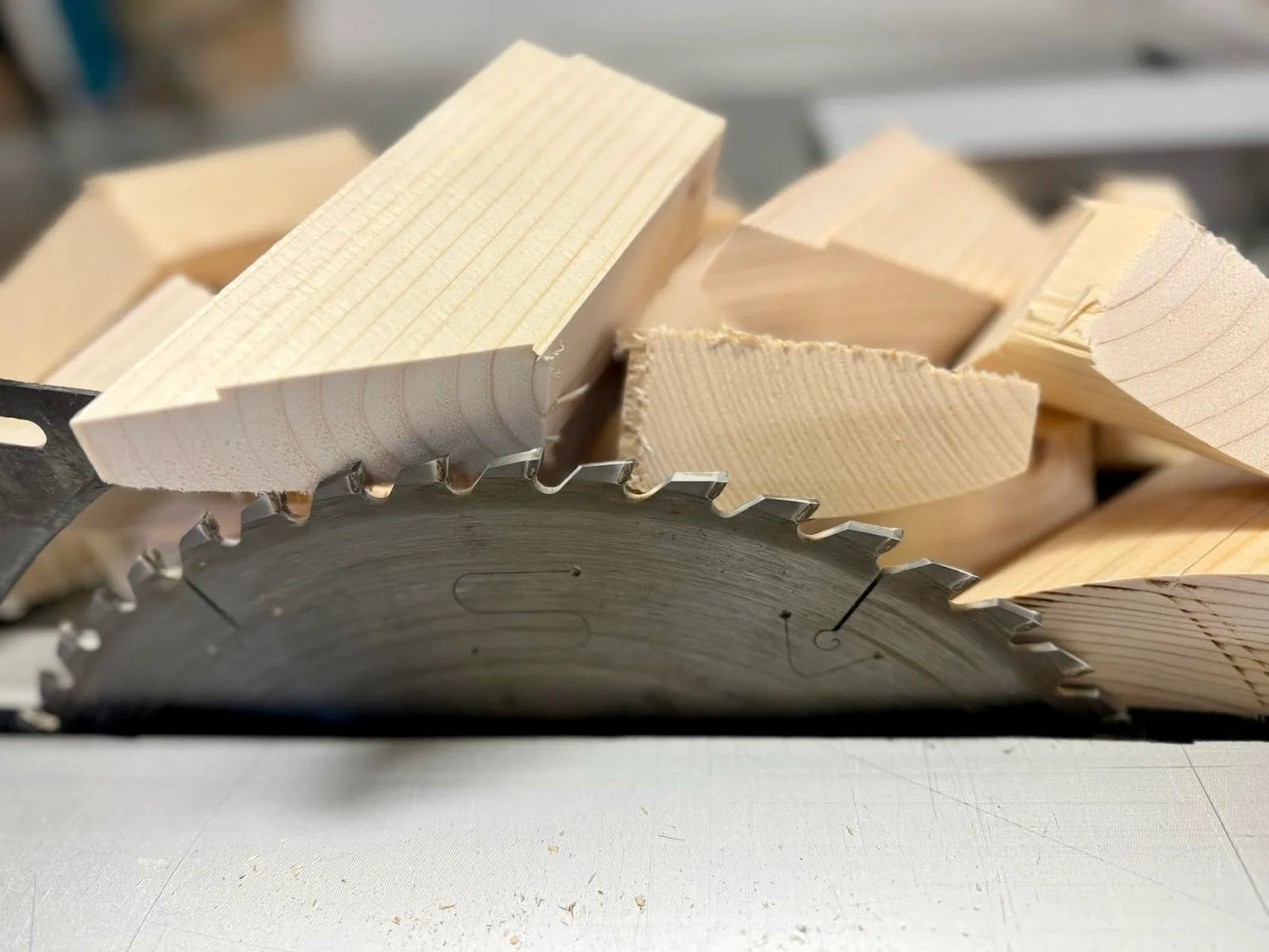 Detailaufnahme frisch geschnittener Fichtenholzstücke auf einer Kreissäge in der Tischlerei. Das Holz dient als Ausgangsmaterial für handgefertigte Rahmen.