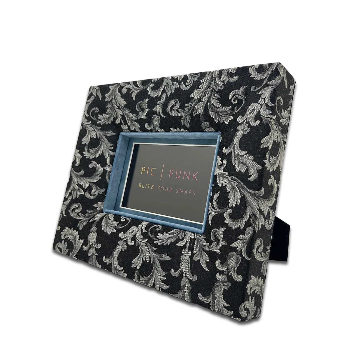 Querformatiger Bilderrahmen aus schwarzem Jacquard-Stoff mit weißem/hellgrauen Barockmuster und kontrastierendem hellblauem Inlay – eleganter Stoffrahmen für stilvolle Wohnaccessoires und Interior Design.
Für 10x15cm Fotos.