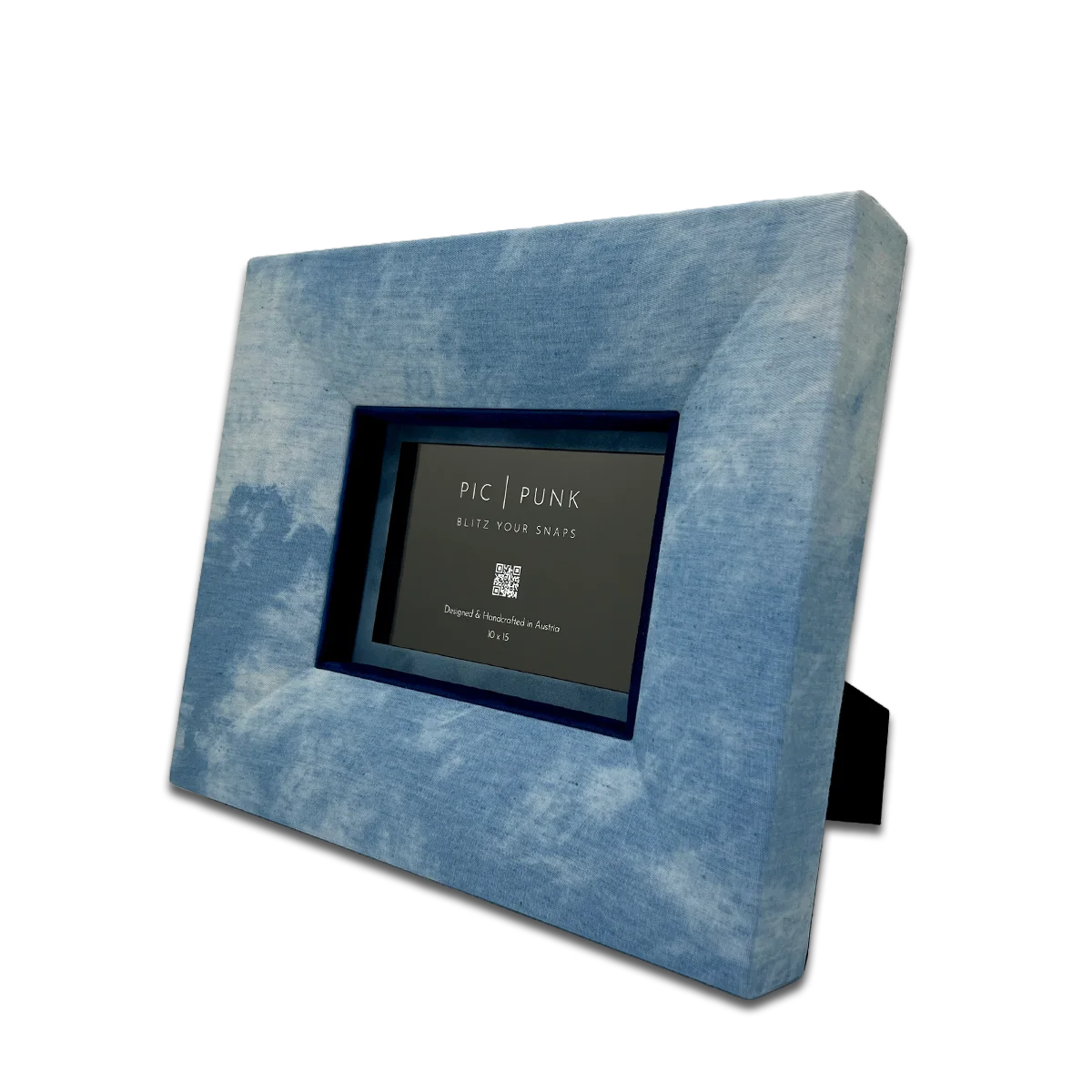 Handgefertigter Design-Bilderrahmen aus hellblauem Denim-Stoff in schräger Ansicht, mit tiefblauem Inlay und moderner, klarer Linienführung. Der Stoff-Fotorahmen „Billy Jean“ von PIC | PUNK eignet sich für Fotos im Format 10 × 15 cm und verbindet urbanen Denim-Look mit hochwertigem Interior-Design. Jedes Stück wird in Österreich von Hand gefertigt und ist ein einzigartiges Wohnaccessoire für stilvolle Wand- und Tischdekoration, moderne Wohnräume, kreative Galeriewände und besondere Geschenkideen.