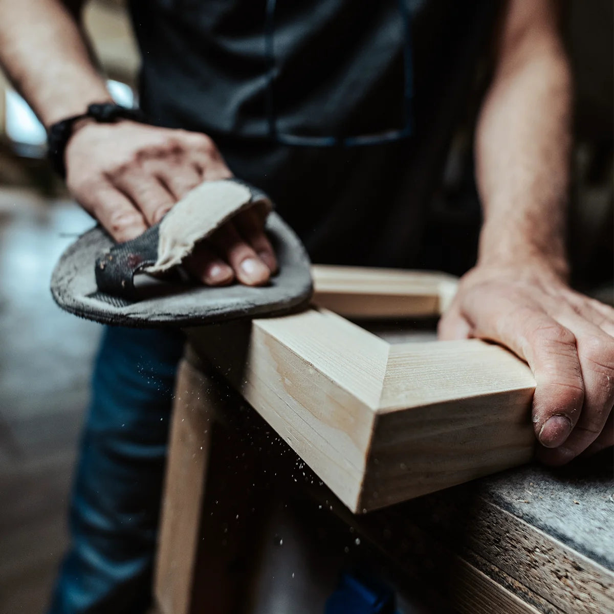 Tischler schleift einen hölzernen Rohrahmen von Hand in der Werkstatt. Detailaufnahme der handgefertigten Rahmenproduktion von PIC | PUNK in Österreich.